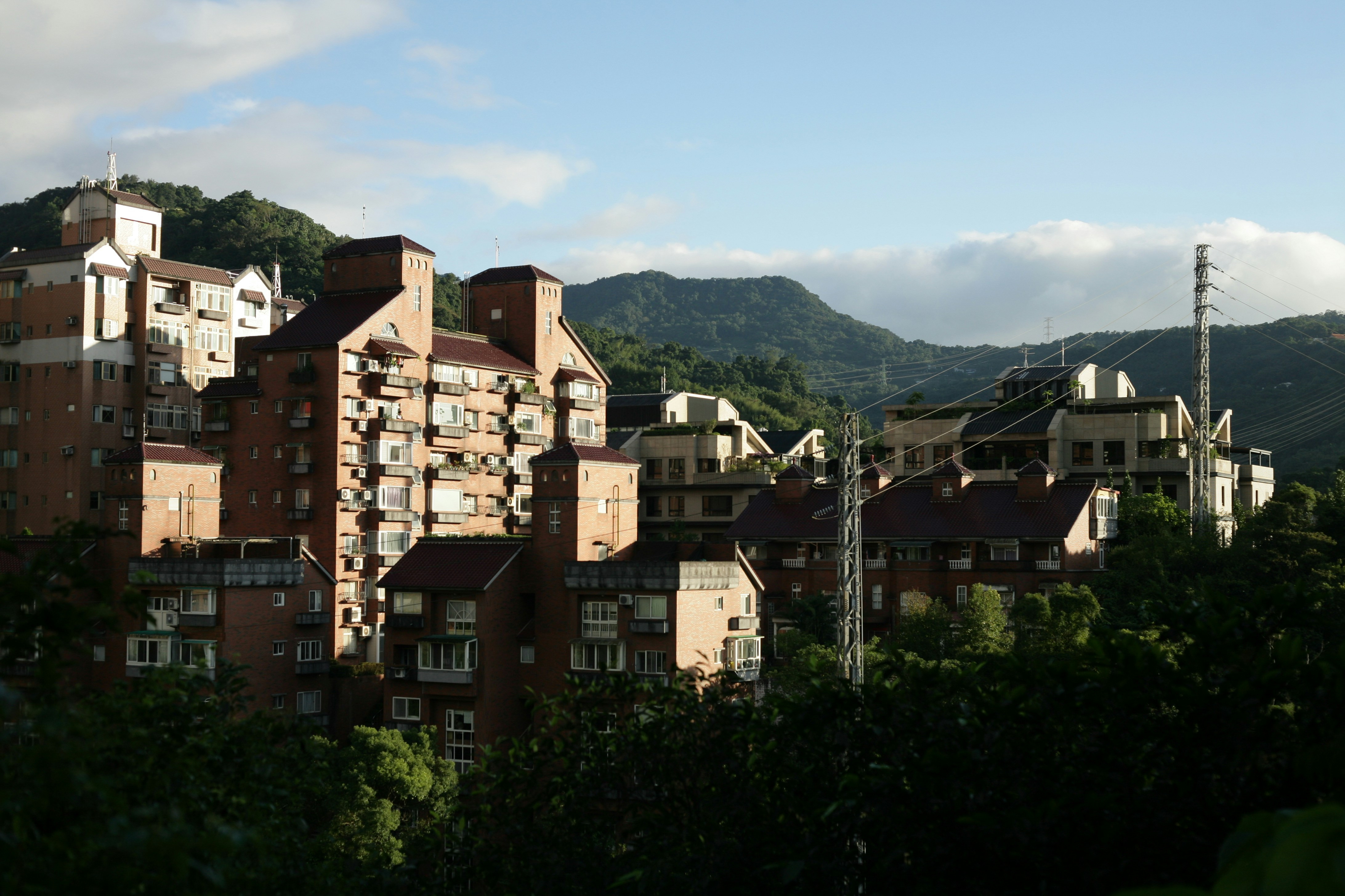 brown concrete buildings near green trees under blue sky during daytime
